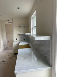 an empty kitchen with white cabinets and marble counter tops in the foreground is being remodeled