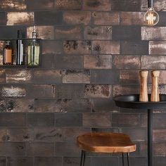 a wooden stool sitting in front of a brick wall with bottles on top of it