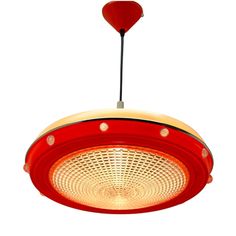 a red and yellow light hanging from a ceiling fixture with a heart shaped object above it