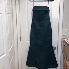 a black dress hanging on a hanger in front of a door with a drawer