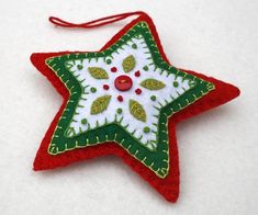 a red and green christmas ornament hanging on a white tablecloth covered surface