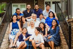 a group of people sitting on the steps of a house posing for a photo with their arms around each other