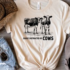 Easily Distracted by Cows Shirt - Farm Shirt - Cow Shirt - Homesteader Shirt - Farm Girl - Farm Girl Shirt - Cow Lover Shirt - Country Girl Adult T-Shirts: Bella and Canvas 3001C and 3001CVD.  100% airlume and ring spun cotton.  Heathers are 52% airlume combed and ring spun cotton 48% polyester. Side seamed, pre-shrunk.  Unisex sizing.  Tear away label.   Ladies Racerback Tanks: Bella and Canvas tanks.  100% airlume combed and ring spun cotton. Heather colors are 52% airlume combed and ring spun Casual Cow Print Tops With Relaxed Fit, Unisex Casual Shirt With Funny Print, Short Sleeve Cotton Tops With Cow Print, Casual Crew Neck Cow Print Tops, Casual Short Sleeve Cow Print Tops, Cow Shirts Vinyl, Casual Cow Print Crew Neck Top, Cotton Crew Neck Top With Cow Print, Farm Life Shirts