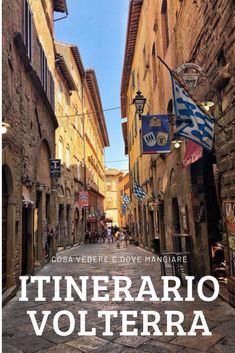 an alley way with flags hanging from the buildings and cobblestone streets in italy