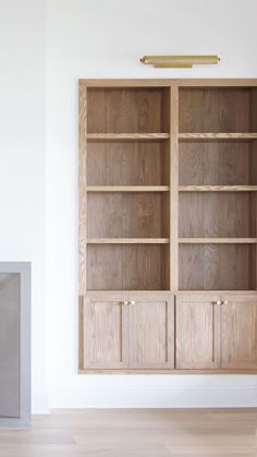 an empty room with a wooden bookcase and fireplace