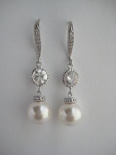 Classic cubic zirconia and pearl bridal earrings in rhodium plated brass setting. Earrings feature 10mm Swarovski white pearl drop that dangles from crystal encrusted ear wire and round cubic zirconia connector. Total length of the earrings is 4 cms . For matching necklace click: https://www.etsy.com/listing/252984768/white-pearl-and-crystal-bridal-necklace?ref=shop_home_active_7 For matching bracelet click: https://www.etsy.com/listing/253901956/classic-bridal-white-pearl-bracelet?ref=shop_home Classic Crystal Bridal Earrings With Pearl Drop, Classic Cubic Zirconia Pearl Earrings For Wedding, Classic Pearl Earrings With Cubic Zirconia For Wedding, Silver Classic Pearl Earrings For Wedding, Classic Silver Pearl Earrings For Wedding, Silver Pearl Chandelier Earrings For Anniversary, Classic Dangle Pearl Earrings With Cubic Zirconia, White Gold Cubic Zirconia Pearl Earrings For Wedding, Classic Silver Bridal Earrings With Pearl Drop