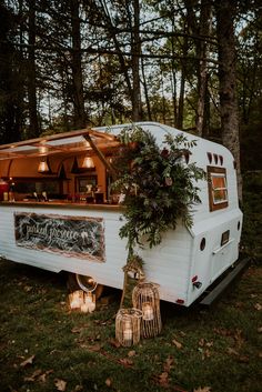 the food truck is decorated with greenery and candles for an outdoor wedding reception in the woods