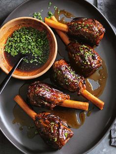 a plate with some meat and carrots on it next to a bowl of sauce