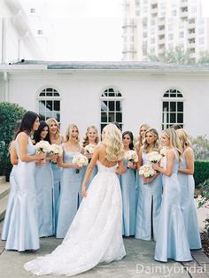 a bride and her bridal party in front of a white building