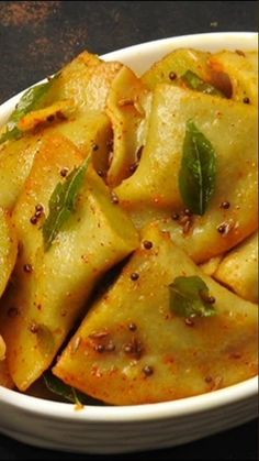 a white bowl filled with pasta covered in sauce and herbs on top of a table