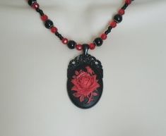 "This beautiful red rose necklace has red glass beads, black glass beads, seed beads, silver plated bead caps, black metal chain and a black metal pendant with red rose cameo. 20\" long. Lobster clasp. gothic art deco victorian renaissance art nouveau style" Gothic Black Bead Necklace For Gift, Gothic Black Beads Necklace For Gift, Gothic Beaded Necklace For Gift, Antique Red Beaded Necklaces For Gift, Antique Red Beaded Necklace For Gift, Black Necklace With Rose Design As Gift, Black Necklace With Rose Design For Gift, Vintage Black Necklace For Valentine's Day, Art Nouveau Necklaces