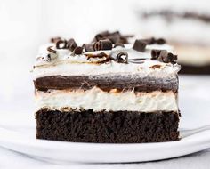 a piece of chocolate cake with white frosting and oreo pieces on top is sitting on a plate