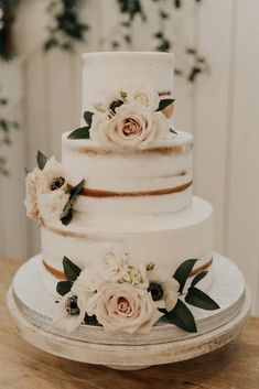 a three tiered wedding cake with flowers on top