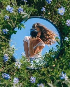 a woman taking a selfie in front of a mirror with blue flowers around her