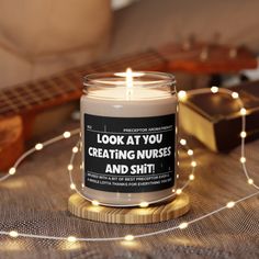 a lit candle sitting on top of a wooden table next to a string of lights