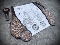 an intricately designed pair of scissors sits on a piece of paper next to another tool