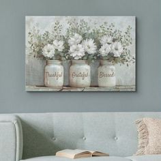 three mason jars with flowers in them sitting on a couch