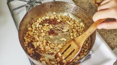 a frying pan filled with food on top of a stove next to a wooden spatula