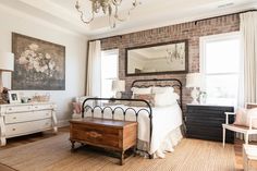 a bedroom with brick walls, white furniture and a chandelier hanging from the ceiling