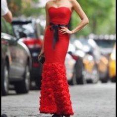 a woman in a red dress is standing on the street