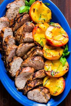 a blue plate topped with meat and veggies on top of a wooden table