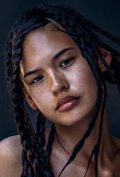 a woman with long braids is posing for the camera