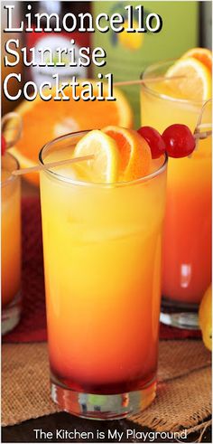 two glasses filled with orange juice and garnished with cherries on the rim