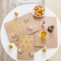 bees and honeycombs cut out on brown paper next to a bowl of honey