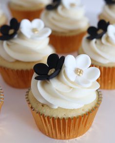 cupcakes with white frosting and black flowers on them are displayed in an instagram