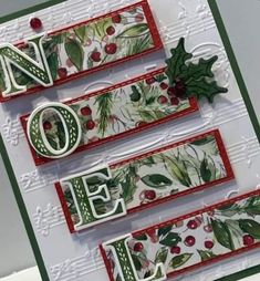 a christmas card with the word noel written in white and green letters, decorated with holly leaves