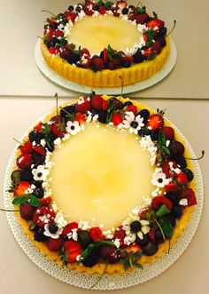 two pies are decorated with fresh fruit and flowers on top of each other, ready to be eaten