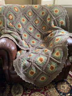 a couch with a blanket on top of it and a brown leather chair next to it