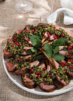 a platter filled with meat and vegetables on top of a cloth covered tablecloth