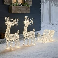 three lighted reindeers in front of a house with christmas decorations on the windowsill