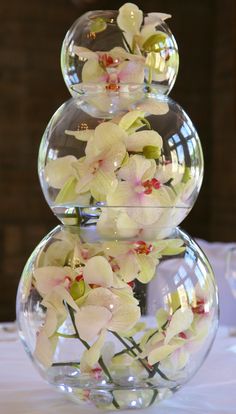 three clear vases filled with flowers on top of a table