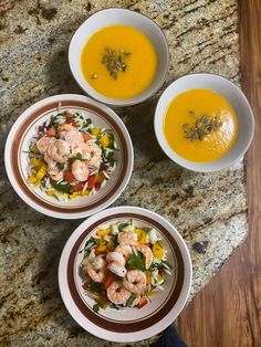 three bowls filled with soup and shrimp on top of a granite counter next to a bowl of soup