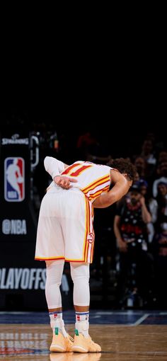 a basketball player standing on the court with his head in his hands and looking down