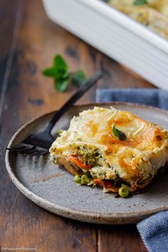 a piece of quiche on a plate with a fork next to it and a casserole dish in the background