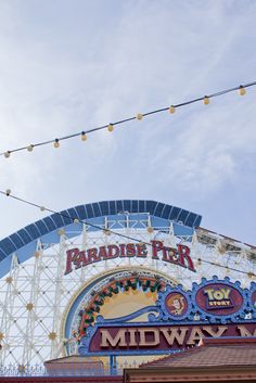 the sign for paradise pier is hanging above the entrance to the midway magic ride park