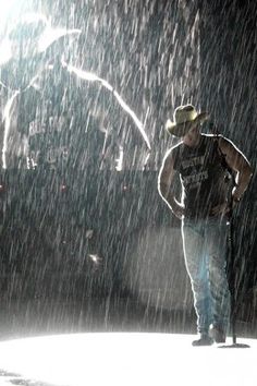 a man standing in the rain wearing a cowboy hat