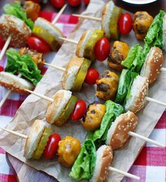 several skewers filled with different types of food sitting on top of a red and white checkered table cloth