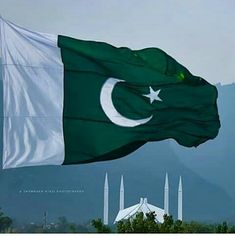 the flag of pakistan is flying in front of some hills and trees with mountains in the background