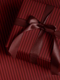 a red and black striped gift box with a brown ribbon on it's side