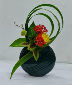 a green vase filled with flowers on top of a white table