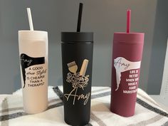 three different types of travel mugs on a table with a checkered blanket and chair in the background