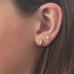 a woman's ear with two small stars on the top and one smaller star on the bottom