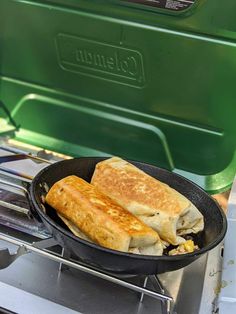 two quesadillas cooking in a skillet on an outdoor stove with the lid open