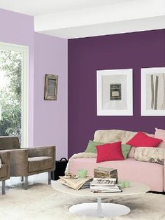 a living room with purple walls and white carpeted flooring, two chairs and a couch