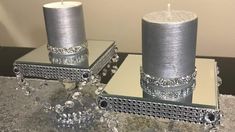 two silver candles sitting on top of a table next to each other with crystal beads around them