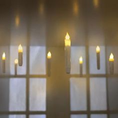 several candles are lit in front of a window